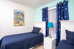 1 dormitorio con 2 camas y cortinas azules en Family Friendly 4 Bedrooms with GameRoom close to Disney in Compass Bay 5103, en Kissimmee