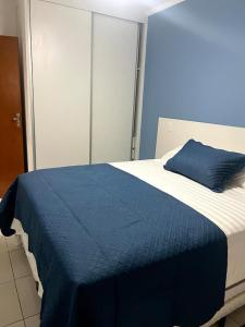 ein blau-weißes Bett mit einem blauen Kissen darauf in der Unterkunft Apto Vista Mar Varanda Gourmet in Praia Grande