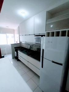 eine Küche mit weißen Schränken und einem weißen Kühlschrank in der Unterkunft Apto Vista Mar Varanda Gourmet in Praia Grande