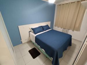 ein blaues Schlafzimmer mit einem Bett mit blauer Bettwäsche und Kissen in der Unterkunft Apto Vista Mar Varanda Gourmet in Praia Grande