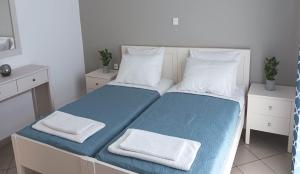 a bedroom with a bed with blue sheets and white pillows at JP Pool & Apartments in Kardamaina