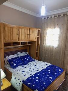 a bedroom with a bed with blue sheets and a window at Gallaghers city ( YameHome ) in Bangangté
