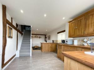 una cocina con armarios de madera y una escalera en Immaculate barn annexe close to Stansted Airport en Great Dunmow