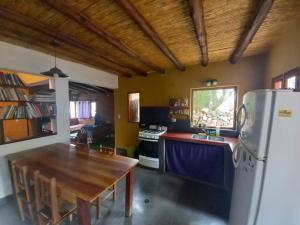 a kitchen with a wooden table and a refrigerator at Cabañas La Esther Tilcara in Tilcara
