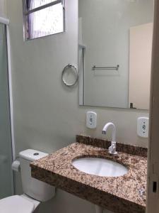 a bathroom with a sink and a toilet and a mirror at Hotel Casa Branca in Uruguaiana
