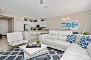 uma sala de estar com mobiliário branco e uma cozinha em Stunning 4 Bd w/ GameRoom Close to Disney 5110K em Kissimmee