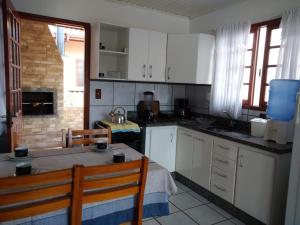 cocina con armarios blancos, mesa y sillas en Apartamento praia da Armação, Florianópolis, en Florianópolis