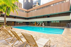 uma piscina com espreguiçadeiras em frente a um edifício em Hale Kekai on Bishop 2412 - 30-Day Minimum em Honolulu