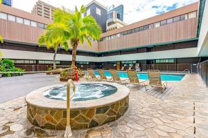 un cortile con piscina e sedie e un edificio di Hale Kekai on Bishop 2412 - 30-Day Minimum a Honolulu