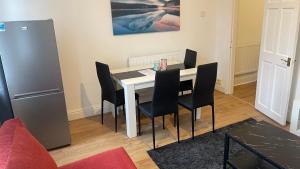 une salle à manger avec une table blanche et des chaises noires dans l'établissement POTTERS LODGE by Edl Ventures Ltd, à Manchester