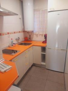 cocina con encimeras de naranja y nevera blanca en Apartamento Ideal, en Madrid