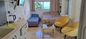 Habitación pequeña con cama, mesa y sillas en הרוגע שלי בבית רובינזון en Nahariyya