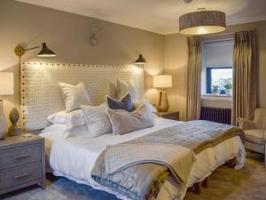 a bedroom with a large white bed with pillows at The Old Stables in Howwood