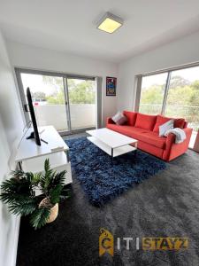 sala de estar con sofá rojo y TV en Bold in Bruce - 1bd 1bth 1csp en Belconnen