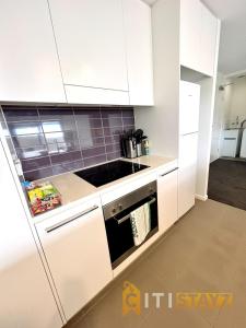 a kitchen with white cabinets and a stove top oven at Bold in Bruce - 1bd 1bth 1csp in Belconnen