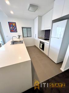 a kitchen with white cabinets and a white refrigerator at Bold in Bruce - 1bd 1bth 1csp in Belconnen