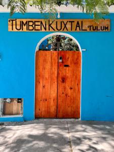 un edificio azul con una gran puerta de madera en Tumben Kuxtal Tulum, en Tulum