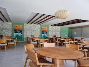 a dining room with wooden tables and chairs at Mana Beach Resort Muro Alto - vista piscina fantastico -e Makia beach in Porto De Galinhas