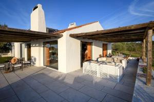 a patio with white chairs and a house at Monte “SERRA E MAR” in Melides