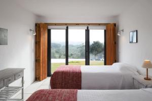 a bedroom with two beds and a large window at Monte “SERRA E MAR” in Melides