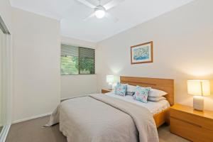 a white bedroom with a bed with two pillows at Little Cove Currumbin in Gold Coast