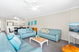 uma sala de estar com sofás azuis e uma mesa em Little Cove Currumbin em Gold Coast