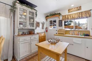 cocina con armarios blancos y mesa de madera en 2283-Cottontail Cottage cabin, en Big Bear Lake