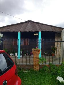 a house with a fence and a red car in front of it at Kitnet SIMIROMBA in Pelotas
