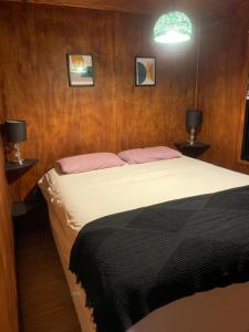 1 dormitorio con 1 cama y 2 mesas con lámparas en Cabaña en entorno natural, en Punta Ballena