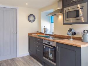 a kitchen with black cabinets and a sink and a microwave at Uk7384 - The Hayloft in Newmilns