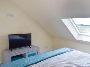 a bedroom with a bed and a flat screen tv at Uk7384 - The Hayloft in Newmilns