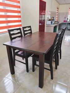 einen Holztisch mit schwarzen Stühlen und eine Küche in der Unterkunft HomeStay Abah Alor Pongsu 
