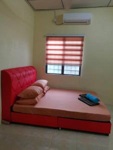 ein rotes Bett in einem Zimmer mit Fenster in der Unterkunft HomeStay Abah Alor Pongsu 