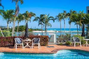 a pool with palm trees and a table and chairs at Little Cove Currumbin in Gold Coast