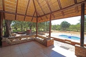 ein Wohnzimmer im Freien mit einem großen Pavillon mit einem Pool in der Unterkunft Twiga Lodge Mabalingwe in Bela-Bela