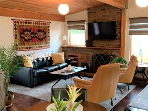 sala de estar con sofá de cuero negro y chimenea en Hilltop Hideaway, Pacific Northwest charm & luxury, en Portland