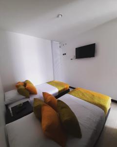 a bedroom with two beds and a tv on the wall at APARTAMENTOS Piscina y Parque del Café in Montenegro