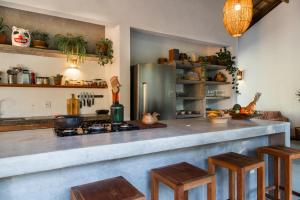 a kitchen with a counter with a stove and stools at Casa Canoa - Praia de Algodões in Marau
