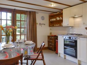 a kitchen with a table with chairs and a stove at Willow Cottage in Kirriemuir