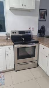 a kitchen with a stainless steel stove and white cabinets at Harloes Luxury Suite - Kingston Jamaica in Kingston