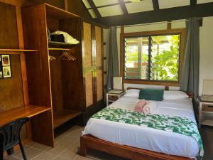 1 dormitorio con 1 cama grande y ventana en Island View Cottages en Luganville