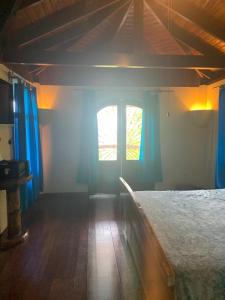 a bedroom with a bed with blue curtains and a window at Casa Papaya in Uvita