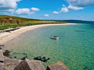 a boat in the water next to a beach at Three Island View - W42427 in Pierowall