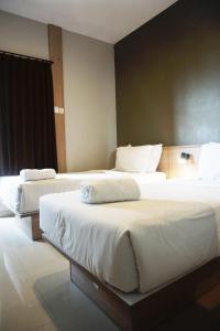 2 camas en una habitación de hotel con sábanas blancas en Kanna Stay, en Semolowaru