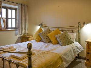 1 dormitorio con 1 cama con almohadas amarillas en Combe Cottage-uk42228, en Low Borrowbridge