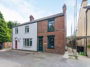 a white and red brick building with a red door at Apple Tree Cottage - Uk37305 in Harrogate