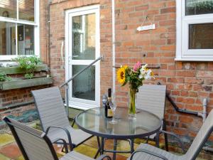 a glass table with a vase of flowers on a patio at Station House in Hornsea