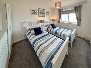 two beds in a small bedroom with a window at Seapoint House in Cleveleys
