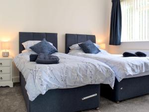 two beds in a bedroom with blue and white sheets at Seascape in Sidmouth