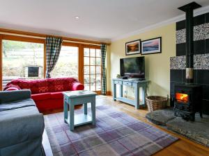 a living room with a red couch and a fireplace at The Barn - S4593 in Lochearnhead